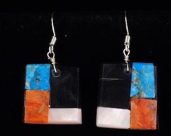 May include: Square earrings with a mosaic design. Each earring features a combination of black, turquoise, orange, and white mother-of-pearl stones. The earrings have silver-coloured hooks.
