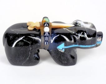 May include: Black obsidian bear carving with turquoise and shell inlay. The bear is wearing a beaded necklace and has a bone knife on its back.