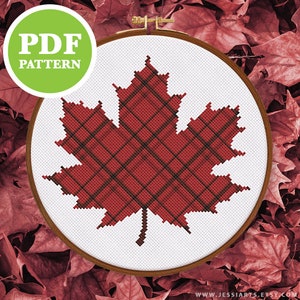 May include: A cross-stitch pattern of a red plaid maple leaf, displayed in a wooden embroidery hoop. The words "PDF PATTERN" are in a green circle in the upper left. The website address is at the bottom.
