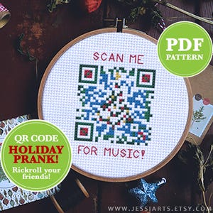 May include: A white embroidery hoop with a cross-stitch design of a QR code that says "Scan Me" and "For Music!"  The QR code is shaped like a Christmas tree.  The hoop is on a wooden surface with green and red Christmas decorations.  The text "QR Code Holiday Prank! Rickroll your friends!" is on a green circle.