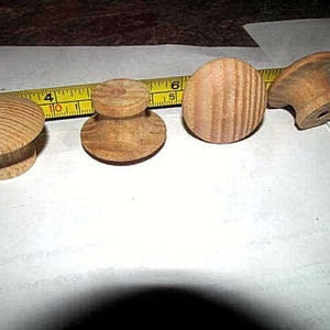 May include: Four wooden knobs with a natural finish. The knobs have a variety of shapes, including round, oval, and mushroom-shaped.