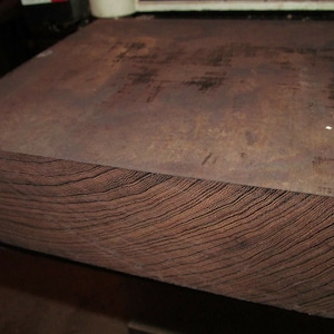 May include: A close-up of a large, dark brown wood block with a smooth, polished surface and visible grain patterns.