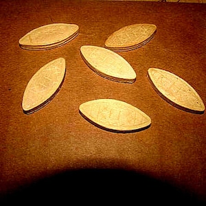 May include: Six light brown wooden oval-shaped pieces with a textured surface.