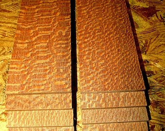 May include: Two stacks of thin, wooden boards with a reddish-brown color and a unique, textured grain pattern.
