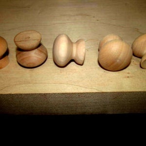 May include: Five wooden knobs in various shapes and sizes. The knobs are unfinished and have a natural wood color.