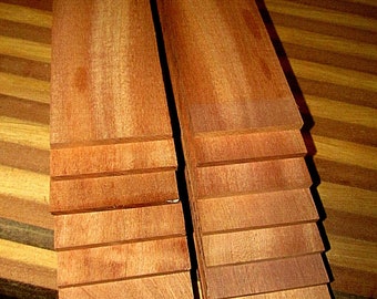 May include: Stacks of reddish-brown wooden planks, likely for woodworking projects. The planks are neatly arranged, showcasing the natural wood grain and color variations. The wood appears to be smooth and ready for use, with a warm, inviting tone.