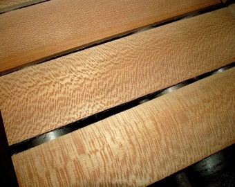May include: Close-up of several pieces of wood with a distinctive grain pattern. The wood is light brown with a reddish hue. The grain is straight and even, with a slight wave pattern.