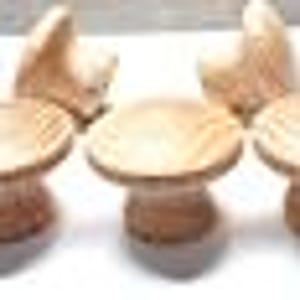 May include: Set of four wooden mushroom-shaped stools with a natural wood finish. The stools are small and would be suitable for children.