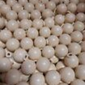 May include: A large quantity of white ceramic round ornaments with a small hole at the top. The ornaments are arranged in a grid pattern.