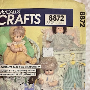 May include: A McCall's Crafts pattern for a complete baby doll wardrobe. The pattern includes sizes for 13"-14", 15"-16", and 17"-18" dolls. The image shows dolls and clothing examples, including dresses and overalls.
