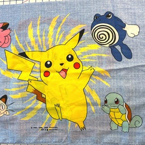 Könnte beinhalten: Ein hellblauer Stoff mit mehreren bunten Pokémon-Charakteren. Die zentrale Figur ist ein gelbes Pikachu mit einem Blitzdesign. Weitere Charaktere sind Clefairy, Meowth, Poliwag und Squirtle.