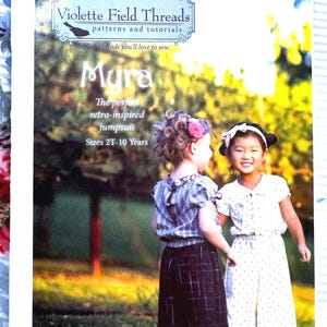 May include: A sewing pattern cover featuring two young girls modeling a retro-inspired jumpsuit. The cover includes the text "Violette Field Threads" and "Mura" with sizes 2T-10 Years. The girls are wearing the jumpsuit in different colors.