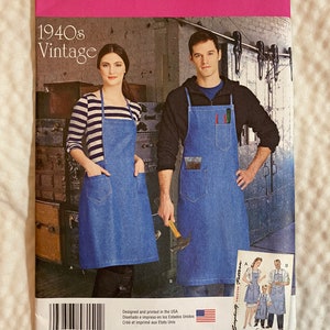 May include: A Simplicity sewing pattern for a 1940s vintage apron. The pattern shows two people wearing denim aprons with pockets. The pattern number is 8151. The text "Designed and printed in the USA" is at the bottom of the pattern.