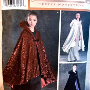 May include: Simplicity Vintage Closet sewing pattern featuring a burgundy cape with a swirling pattern and a large collar. The pattern includes options for capes in black and white, with fur trim. The pattern is labeled "One Size."