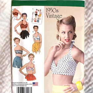 May include: Simplicity 1426 vintage sewing pattern from the 1950s. The pattern features illustrations of various halter tops and skirts. The cover shows a woman in a white polka dot halter top and yellow shorts. The pattern size is U.S. 14-22.