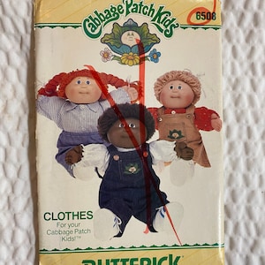 Puede incluir: Un patrón de costura vintage de Cabbage Patch Kids con un logotipo verde y blanco. El patrón es para hacer ropa para las muñecas Cabbage Patch Kids. El número del patrón es 6508. El patrón muestra tres muñecas, una con cabello rojo, otra con cabello rubio y otra con cabello negro. El patrón se titula "Clothes for your Cabbage Patch Kids!" y es de Butterick.