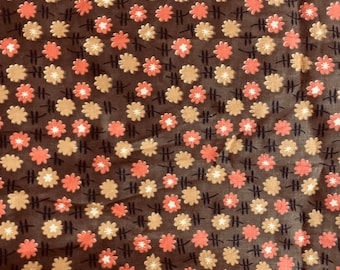 Könnte beinhalten: Ein brauner Stoff mit einem sich wiederholenden Muster aus kleinen orangefarbenen und beigefarbenen Blumen. Der Hintergrund ist dunkelbraun.