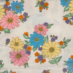 Puede incluir: Tela blanca con un estampado floral repetido. Grandes flores en rosa, amarillo y azul se intercalan con flores moradas y naranjas más pequeñas. Las hojas verdes acentúan las flores, creando un diseño alegre.