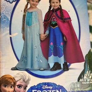May include: Simplicity home sewing pattern featuring two girls dressed as characters from Disney's Frozen. One girl wears a light blue dress with snowflake accents, the other a blue dress with a pink cape. The pattern includes sizes 3-8.