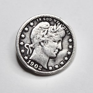 May include: A silver coin from 1902, featuring a profile of a woman with a laurel wreath and the inscription "IN GOD WE TRUST." The coin is surrounded by stars and has a detailed edge.