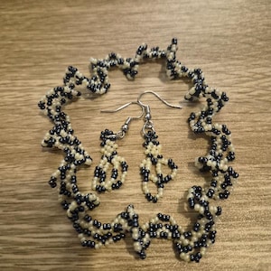May include: A beaded jewelry set featuring a bracelet and earrings. The bracelet and earrings are made with small, round beads in a pattern of navy blue and cream. The earrings have silver-colored hooks. The number "1336" is visible in the lower left corner.