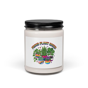 Peut inclure: Une bougie en pot de verre transparent avec un couvercle noir et une étiquette blanche portant le texte PROUD PLANT QUEER en lettres arc-en-ciel au-dessus d'une illustration colorée de cinq plantes en pot aux motifs de drapeaux fiers.