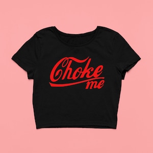 Op de afbeelding: Zwart gecropped T-shirt met een rode "Choke Me" grafische afbeelding in een vintage lettertype.