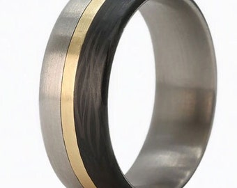 May include: A titanium ring with a black carbon fiber inlay and a thin gold band.
