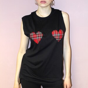 May include: Black sleeveless shirt with two red and black plaid heart patches on the front.