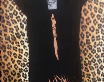 Può includere: Maglietta nera a maniche corte con un design a stampa leopardata marrone e nera. La maglietta ha un collo rotondo e una linea verticale di borchie argentate al centro.