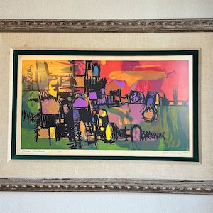 May include: A framed abstract art print with a colorful cityscape scene in shades of yellow, orange, red, green, purple, and black. The print is signed "Sol LeWitt" and dated "1963".