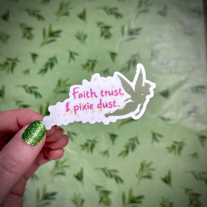 Puede incluir: Una pegatina blanca con una silueta verde de Campanilla y el texto "Faith, trust, & pixie dust." La pegatina está sobre un fondo verde con un patrón de hojas.