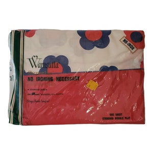 Puede incluir: Una sábana blanca con un estampado floral rojo y azul. La sábana está empaquetada en plástico y tiene una etiqueta que dice "Wamsutta Superl No Ironing Necessary" y "One Sheet Standard Double Flat".