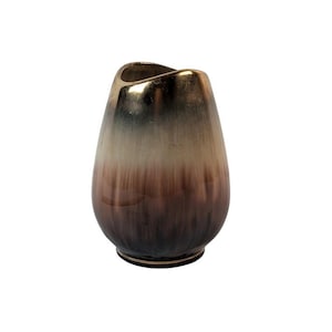 May include: A decorative vase with a teardrop shape. The top of the vase is gold, transitioning to a light brown, and then to a dark brown at the base. The vase has a glossy finish and a unique, organic shape.