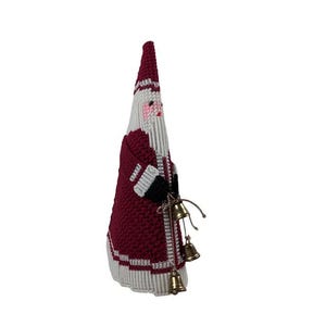 May include: A handmade Christmas decoration in the shape of Santa Claus. The figure is primarily burgundy with white and silver accents. Santa's hat and coat are burgundy, and he has a white beard and face. Small gold bells hang from his hand.