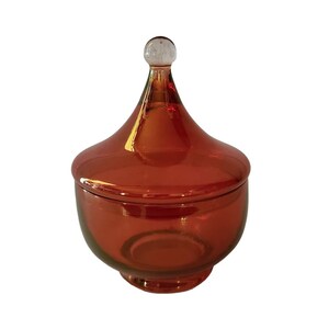 May include: A red glass candy dish with a domed lid and a clear glass knob on top.