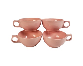 Puede incluir: Juego de cuatro tazas de plástico rosa con asas. Las tazas están apiladas en dos pares.