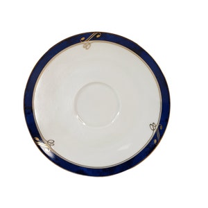 Puede incluir: Un platillo blanco con un borde azul y dorado. El borde tiene un patrón decorativo de remolinos dorados.