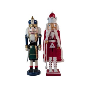 May include: Two wooden nutcracker figurines. The left figure wears a blue and gold crown, a blue jacket with gold accents, and a green kilt. The right figure wears a red and white crown, a red cape, and holds a white staff with silver details.