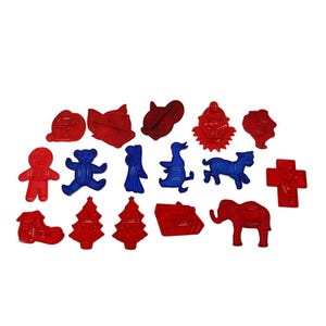 May include: A set of 15 red and blue plastic cookie cutters featuring various holiday and animal shapes, including a gingerbread man, a teddy bear, a Christmas tree, a duck, a reindeer, a cross, a house, an elephant, a cat, a clown, and a fox.