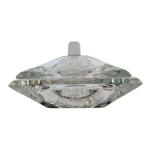 May include: Clear glass trinket box with a geometric design. The box has a lid with a small, rectangular handle. The base of the box is also geometric, with a diamond-like shape. The glass is transparent, allowing a view of the contents.