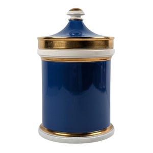 May include: A navy blue ceramic jar with a lid. The jar has gold trim and a white base and lid rim. The lid is navy blue with a gold top. The jar is cylindrical and has a glossy finish.