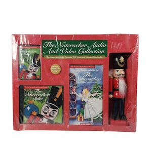 Könnte beinhalten: Eine rote und weiße Box mit einem hölzernen Nussknacker, einem VHS-Band, einer CD und einer Kassette. Die Box ist mit "The Nutcracker Audio and Video Collection" beschriftet.