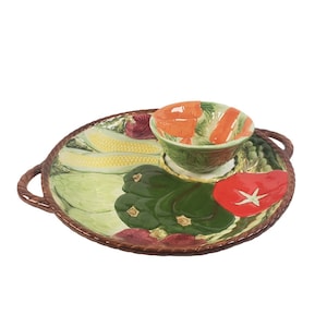 May include: A ceramic serving dish with a removable bowl in the center. The dish is decorated with a colorful vegetable design, including corn, peppers, and zucchini. The bowl is also decorated with vegetables.