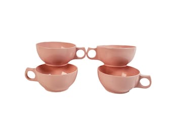 Puede incluir: Conjunto de cuatro tazas de plástico rosa con asas. Las tazas están apiladas en pares.