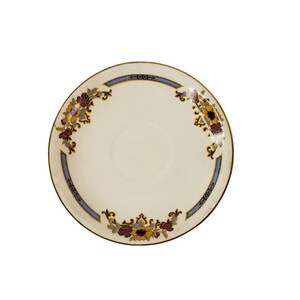 May include: A white ceramic saucer with a gold rim and a blue and gold floral design. The flowers are red, yellow, and brown.