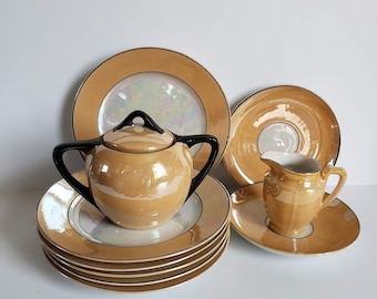 Puede incluir: Un juego de tazas de té y platillos vintage con un glaseado dorado e iridiscente. El juego incluye un azucarero con tapa y una jarra de crema.
