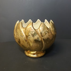 May include: A gold ceramic planter shaped like a flower with a textured surface.