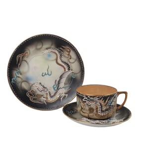 Op de afbeelding: Een vintage theekopje en schotelset met een zwart-wit drakenontwerp. De draak is geschilderd in goud, blauw en rood. De set is gemaakt van porselein.