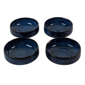 Puede incluir: Cuatro cuencos redondos de cerámica azul oscuro con acabado moteado. Los cuencos tienen un interior brillante y un borde oscuro. Los cuencos están dispuestos en forma cuadrada, perfectos para servir aperitivos o porciones pequeñas.